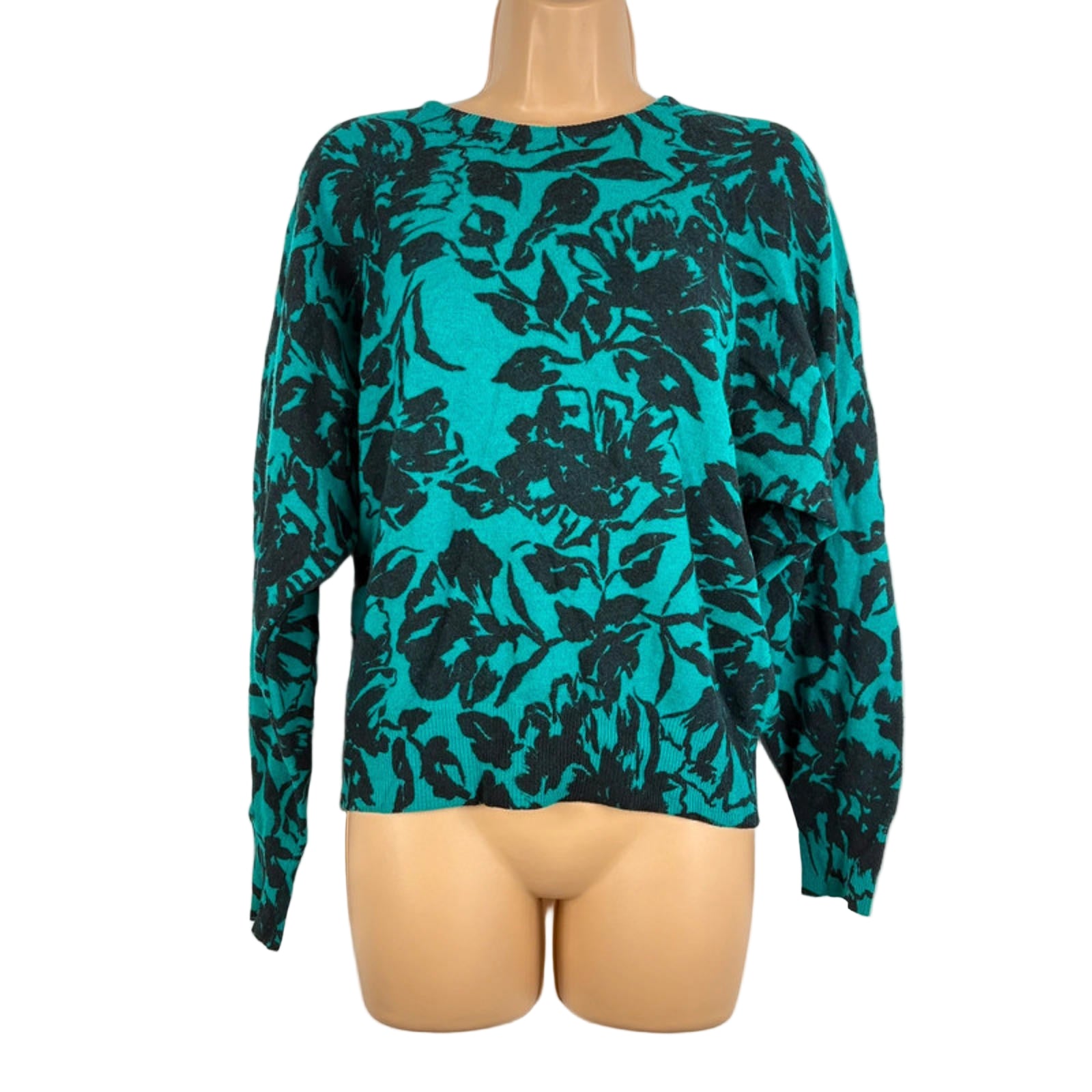 Teal sweater with black floral pattern on a mannequin against a white background