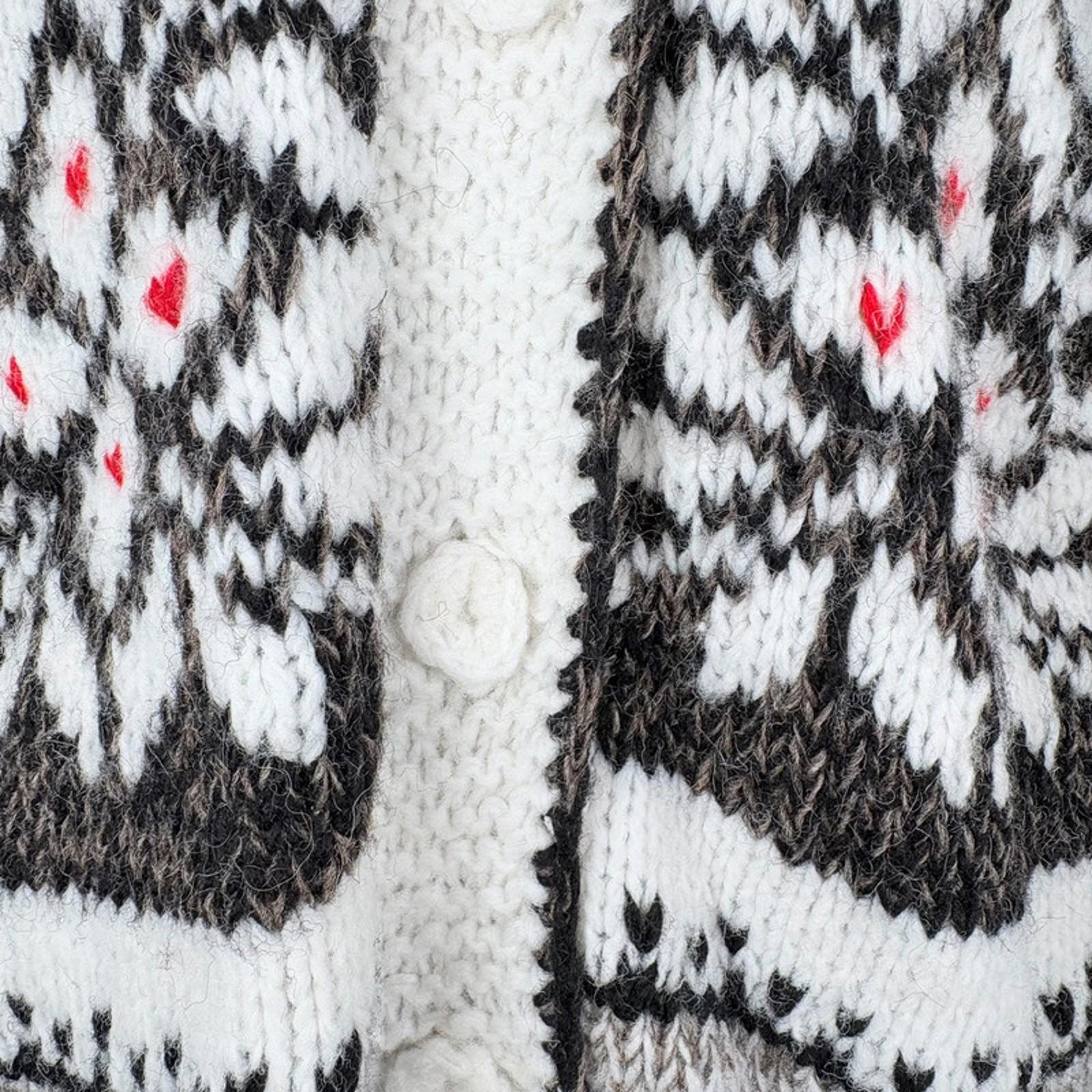Close-up of a knitted garment with a pattern featuring black, white, and red colors.