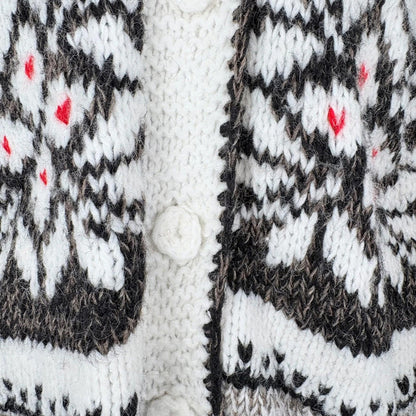 Close-up of a knitted garment with a pattern featuring black, white, and red colors.