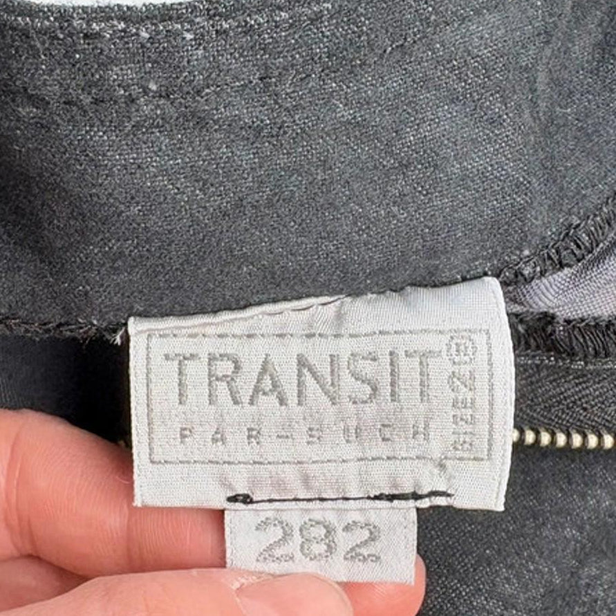 Hand holding a Transit label on a piece of gray fabric