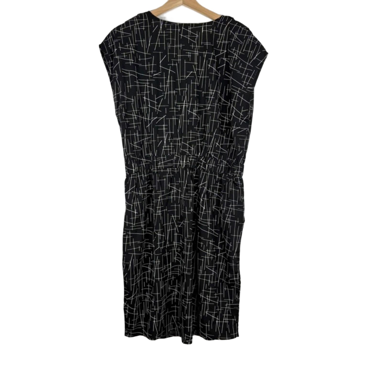 Black dress with white geometric pattern on a hanger against a white background