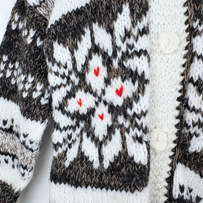 Close-up of a knitted sweater with a pattern featuring black, white, and red colors.