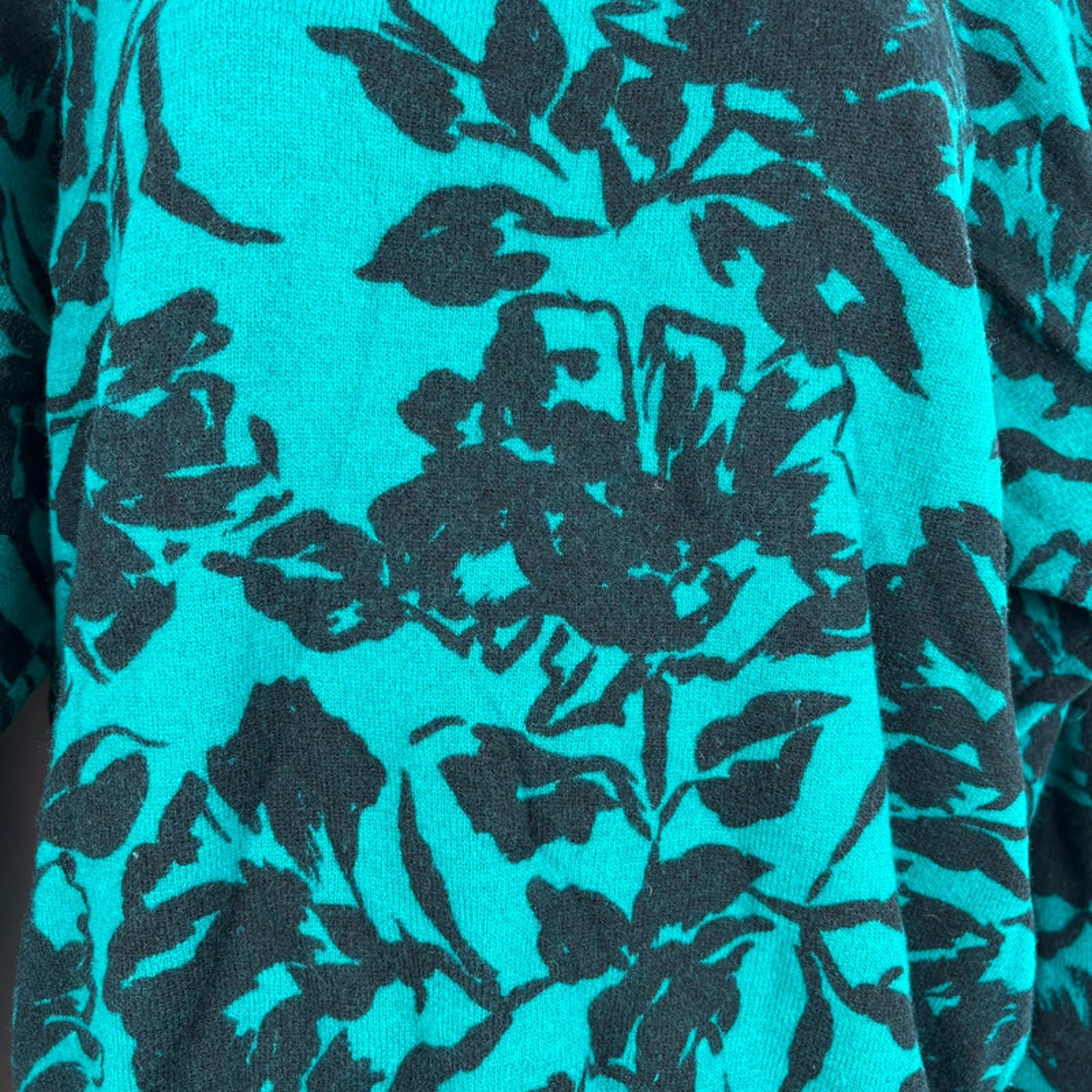Close-up of a fabric with black floral pattern on a turquoise background