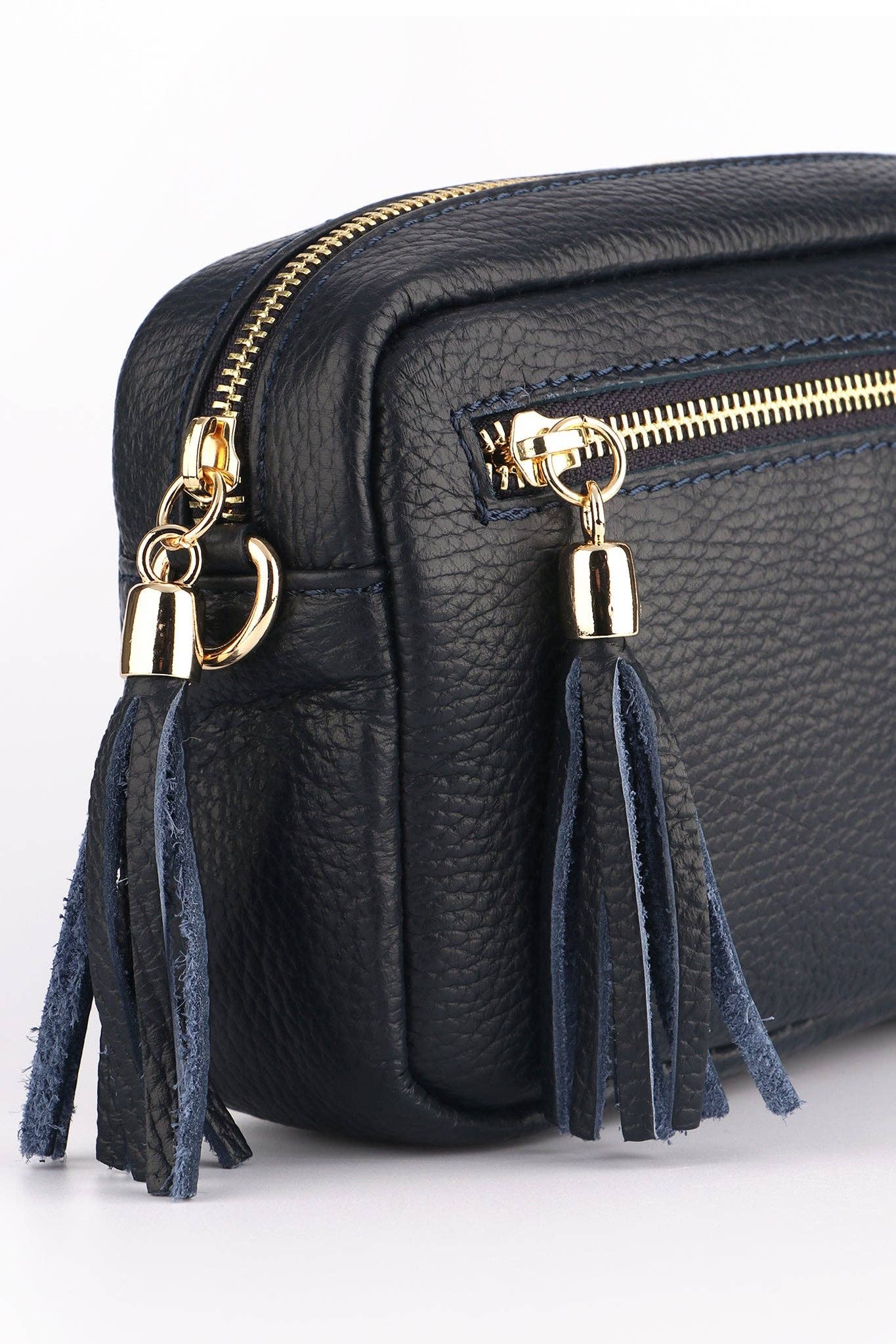 Black leather bag with gold zippers and blue tassels on a white background