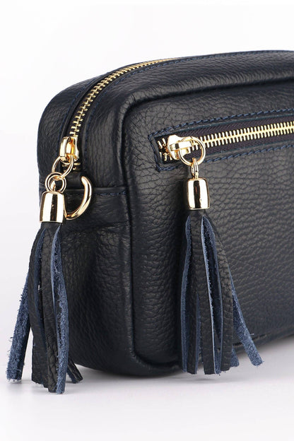 Black leather bag with gold zippers and blue tassels on a white background