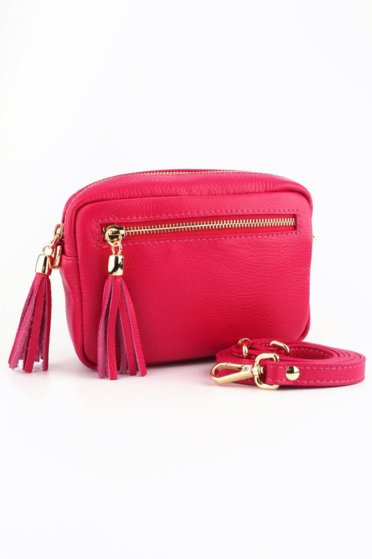 Pink crossbody bag with gold accents and tassels on a white background