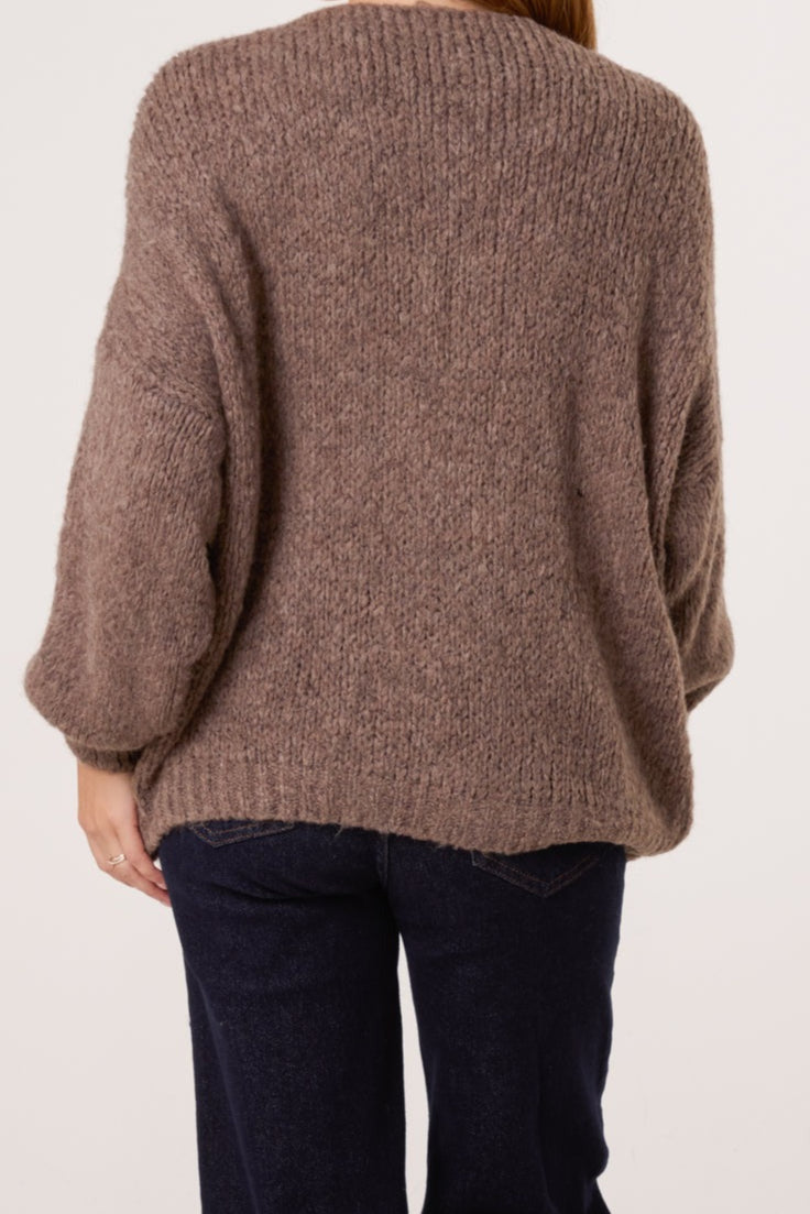 Brown knitted sweater worn by a person on a plain background