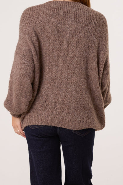 Brown knitted sweater worn by a person on a plain background